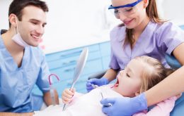 En tandlæge og tandplejer kigger på en piges tænder