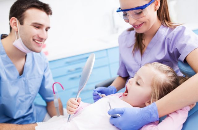 En tandlæge og tandplejer kigger på en piges tænder 